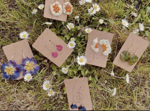 Orecchini in resina con fiori pressati disposti su un prato
