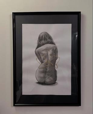 Disegno a carboncino incorniciato di una figura di schiena con dettaglio a filo dorato