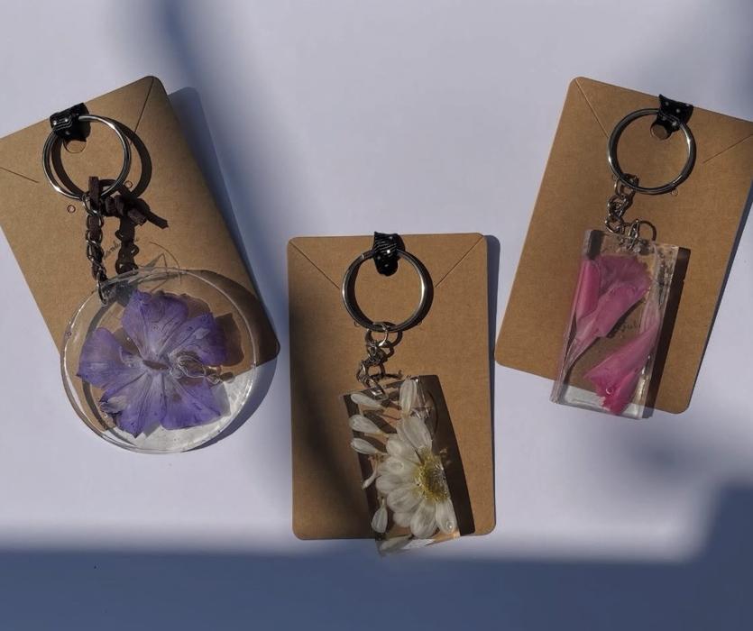 Tre portachiavi in resina con fiori pressati, su cartoncini kraft