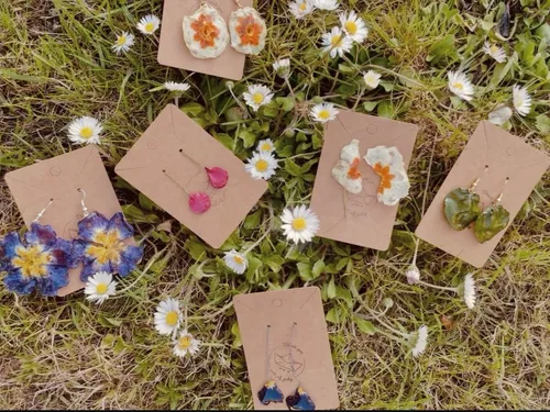 Orecchini in resina con fiori pressati disposti su un prato