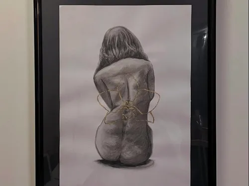 Disegno a carboncino incorniciato di una figura di schiena con dettaglio a filo dorato